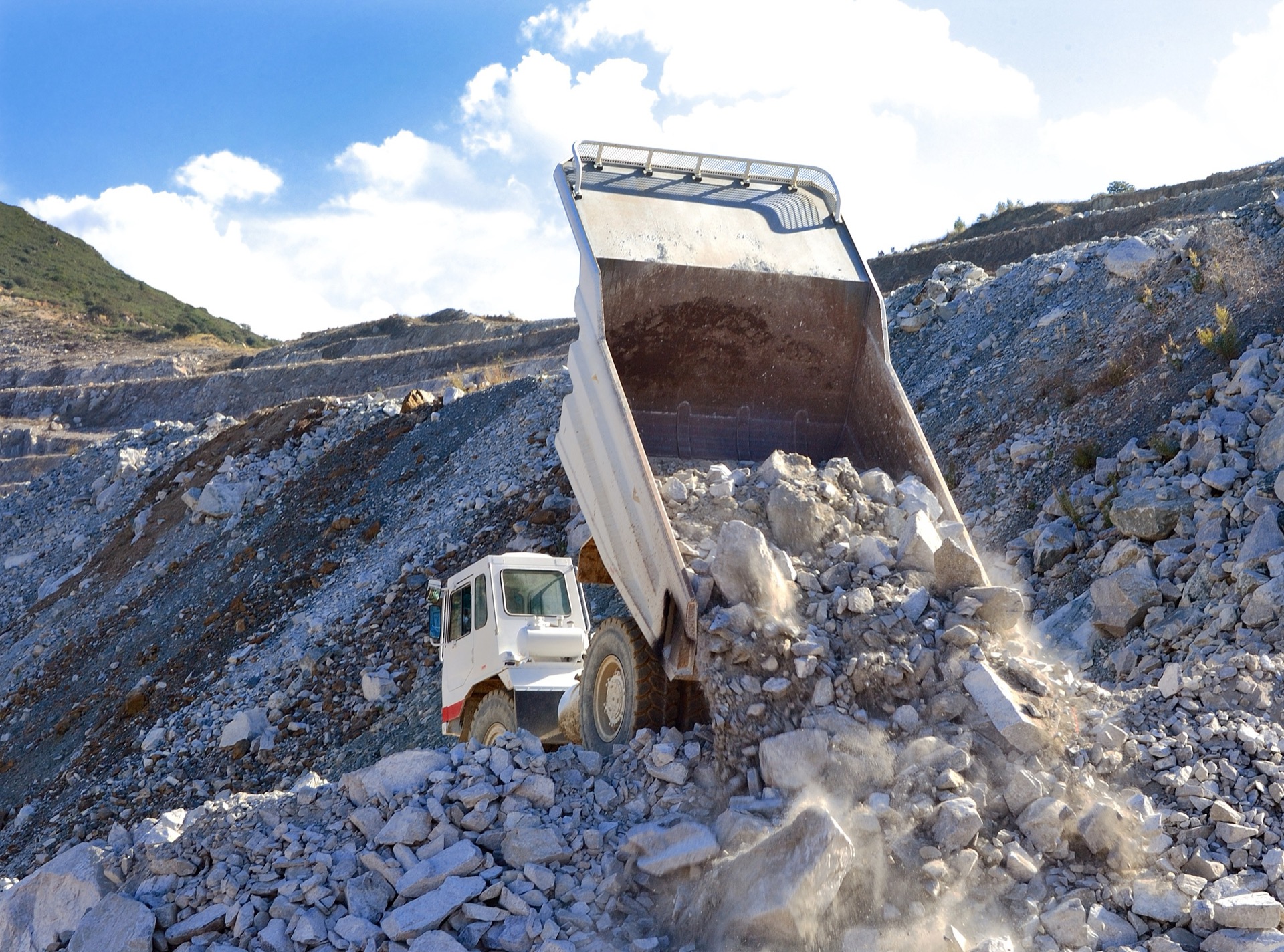 Dump truck unloading rock at a quarry — example heavy vehicle for structural monitoring pilots.